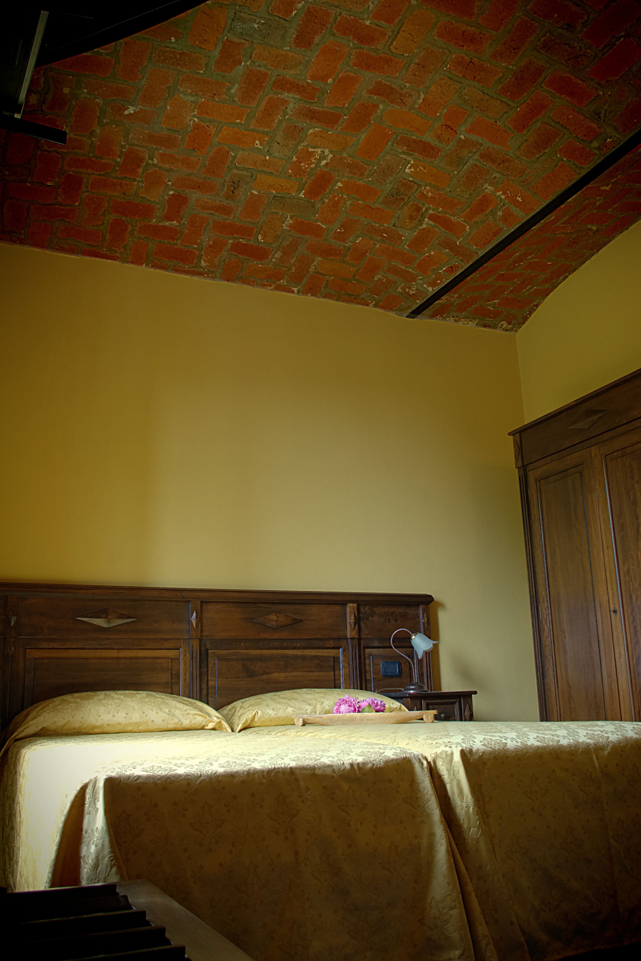 A bedroom with a brick ceiling, wooden headboard, and a bed with a floral bedspread.