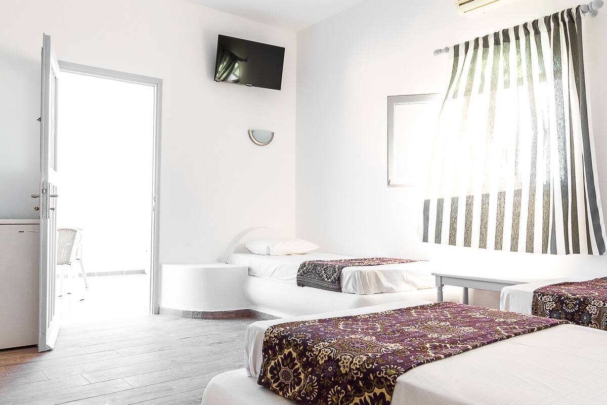 Ein Hotelzimmer mit Bett, Fernseher, Klimaanlage und einem Vorhangfenster.