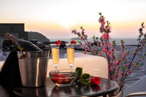 Ein Tisch mit einer Champagnerflasche, zwei Champagnergläsern, einer Schale Erdbeeren und einer Rose.