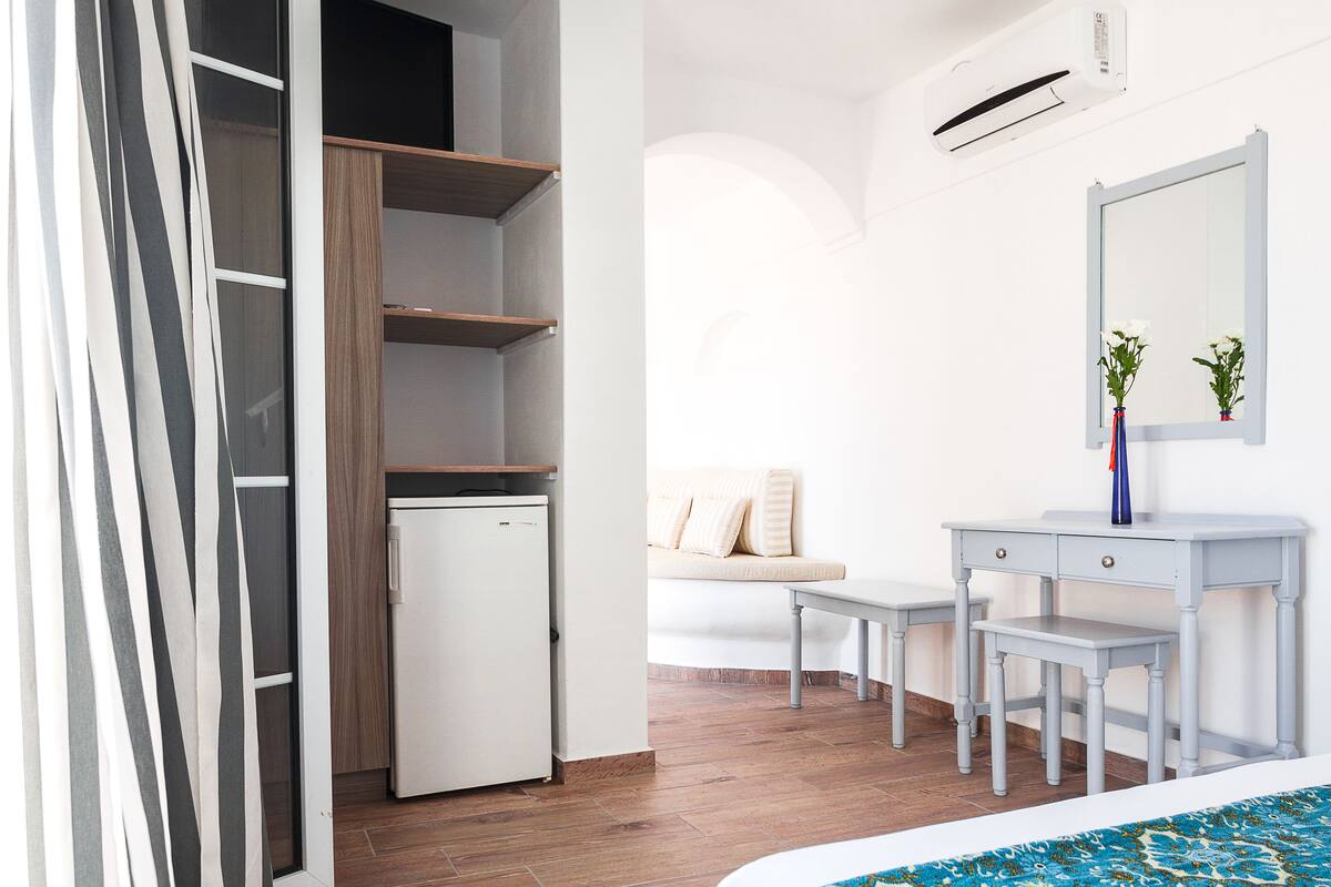 Ein Schlafzimmer mit Bett, Schreibtisch, Kleiderschrank und einem kleinen Kühlschrank.