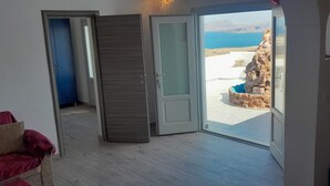 Une pièce dotée d’une porte-fenêtre coulissante donnant sur un balcon avec vue sur une côte rocheuse et la mer.
