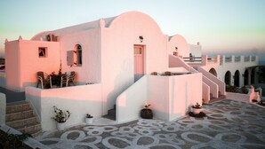 Un bâtiment blanc doté d’un toit incurvé, d’un escalier et de plantes en pot.