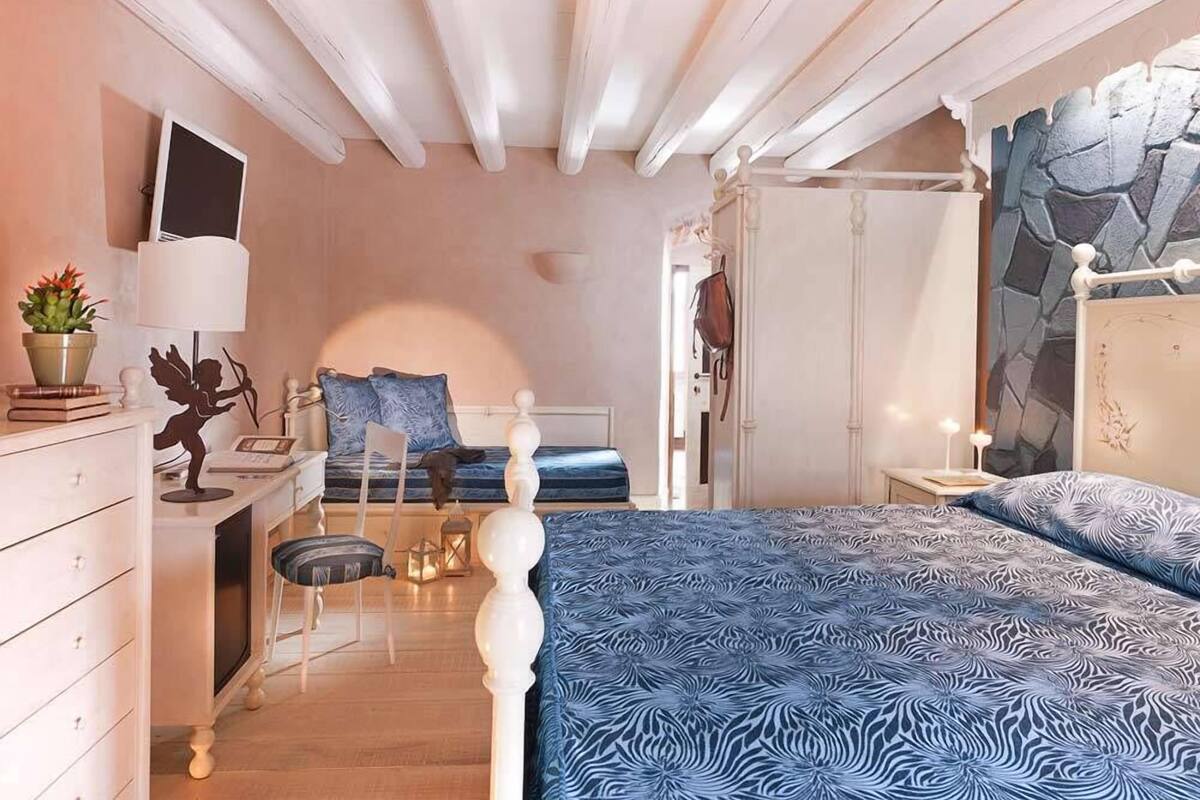 A bedroom with a bed, a desk, a chair, a wardrobe, and a mirror.