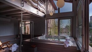 A modern spa area with a hot tub, wooden steps, and large windows offering views of the surrounding landscape. - Boutique Hotel Villa dei Campi (Gavardo)