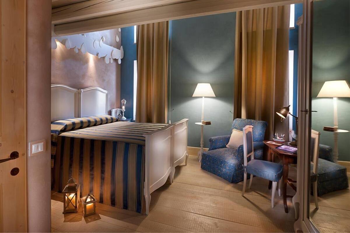 A hotel room with a bed, a chair, a desk, and a lamp.