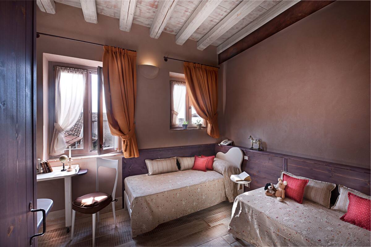 A bedroom with two beds, a desk, and a chair.