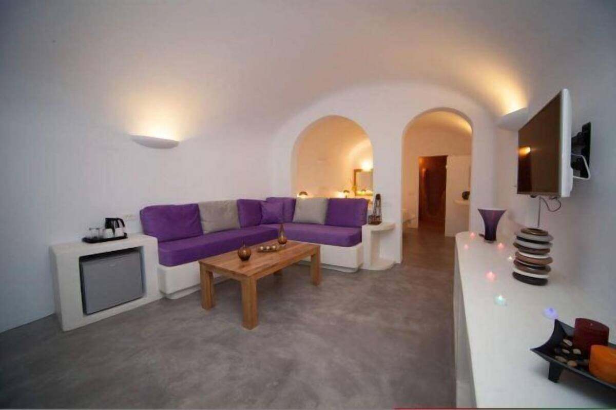 A modern living room with a purple sectional sofa, a wooden coffee table, and a white console table with decorative items.