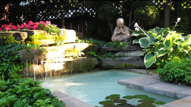 A garden with a pond, a statue, and a stone structure. - Canterbury Inn (Niagara-on-the-Lake)