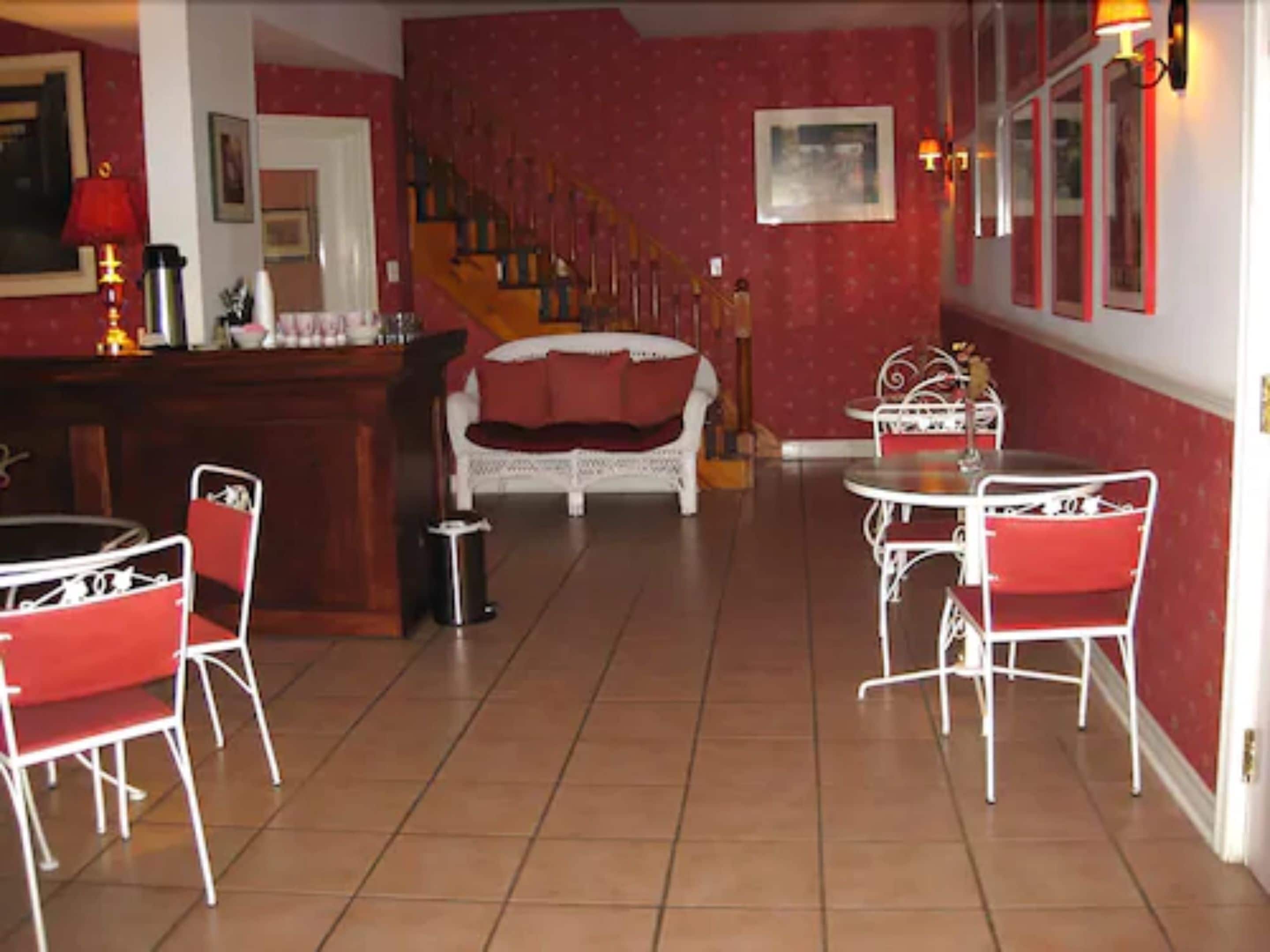 A dining area with red and white furniture, a staircase, and a bar.