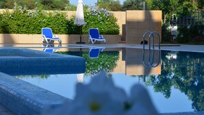Une piscine avec deux chaises longues bleues et un parasol blanc.
