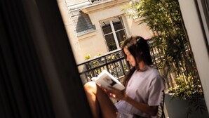A person sitting on a balcony with a view of a building and some plants. - 9Hotel Republique (Paris)