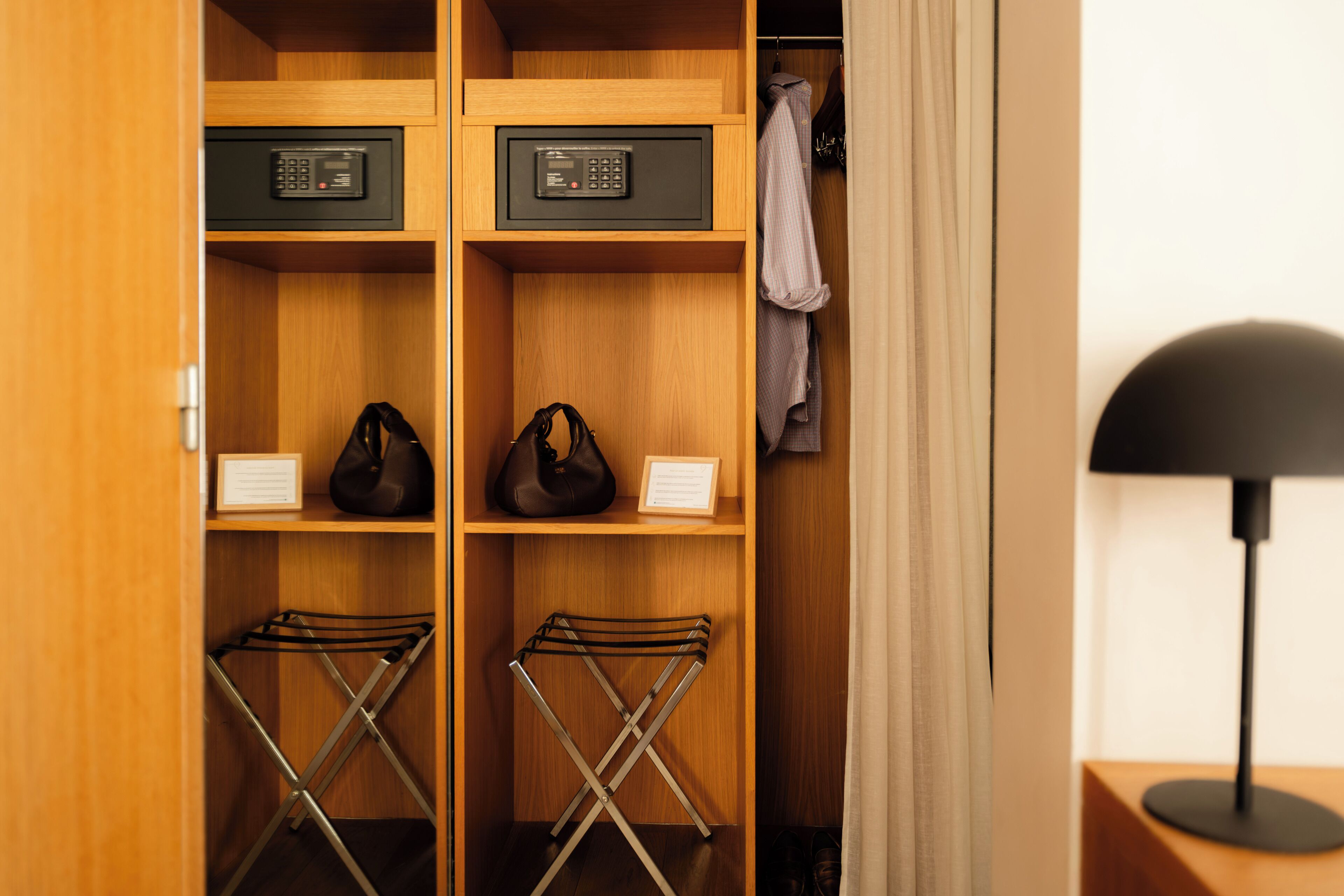 A wooden closet with two electronic devices on shelves, a pair of bags, and a shoe rack.