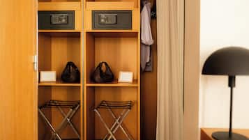 A wooden closet with two electronic devices on shelves, a pair of bags, and a shoe rack.