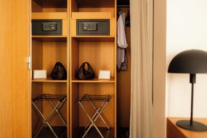 A wooden closet with two electronic devices on shelves, a pair of bags, and a shoe rack.