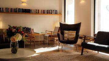 Un salon moderne avec une bibliothèque, une table basse ornée d’un vase de fleurs et deux fauteuils.