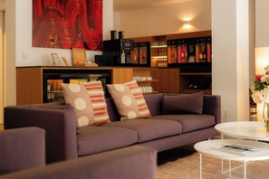 A modern living room with a sofa, armchairs, a coffee table, and a bookshelf.