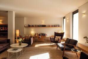 A modern living room with a sofa, chairs, a coffee table, and a bookshelf. - 9Hotel Republique (Paris)