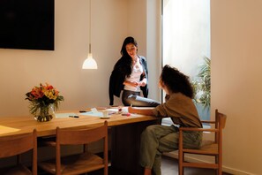 A room with a wooden dining table, chairs, a vase with flowers, and a hanging light fixture. - 9Hotel Republique (Paris)