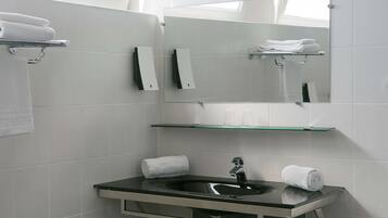 Une salle de bain moderne avec une étagère en verre, un lavabo et un miroir.