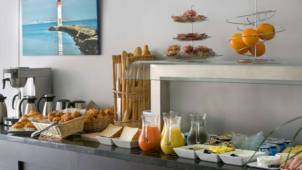 Buffet de café da manhã com pães, doces, frutas e bebidas.