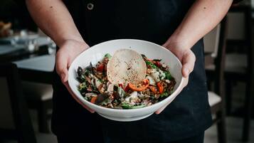 A person holding a bowl of salad with a piece of bread.