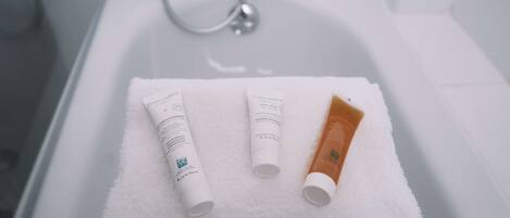 Una vasca da bagno bianca con tre articoli da toilette su un asciugamano bianco.