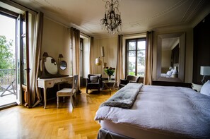 Un dormitorio amplio con una cama grande, un escritorio, una silla y una pequeña mesa con un florero.