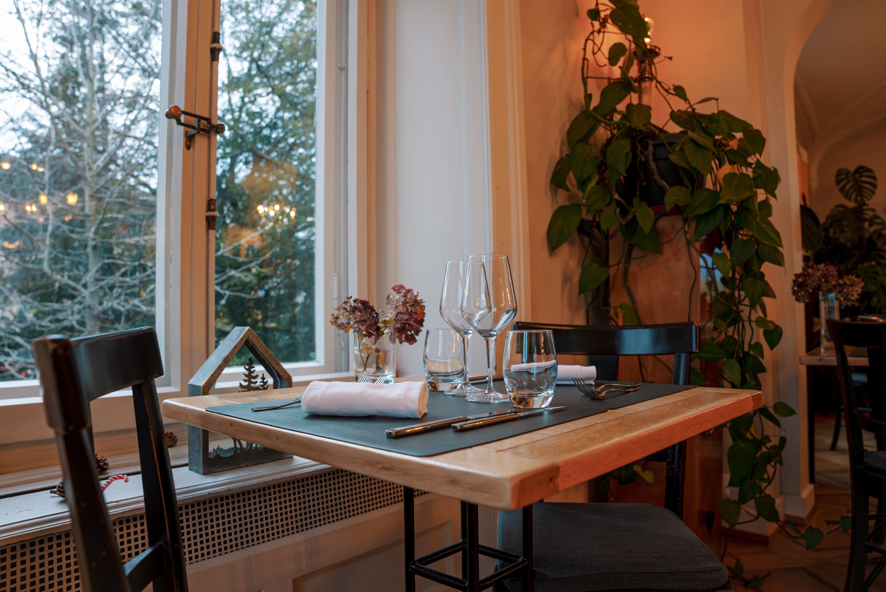 Une table à manger dressée avec des verres à vin, une serviette et un petit objet décoratif.