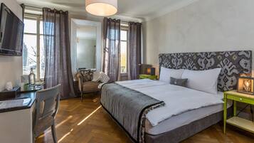 A hotel room with a large bed, a desk with a chair, a TV, and a window with curtains.