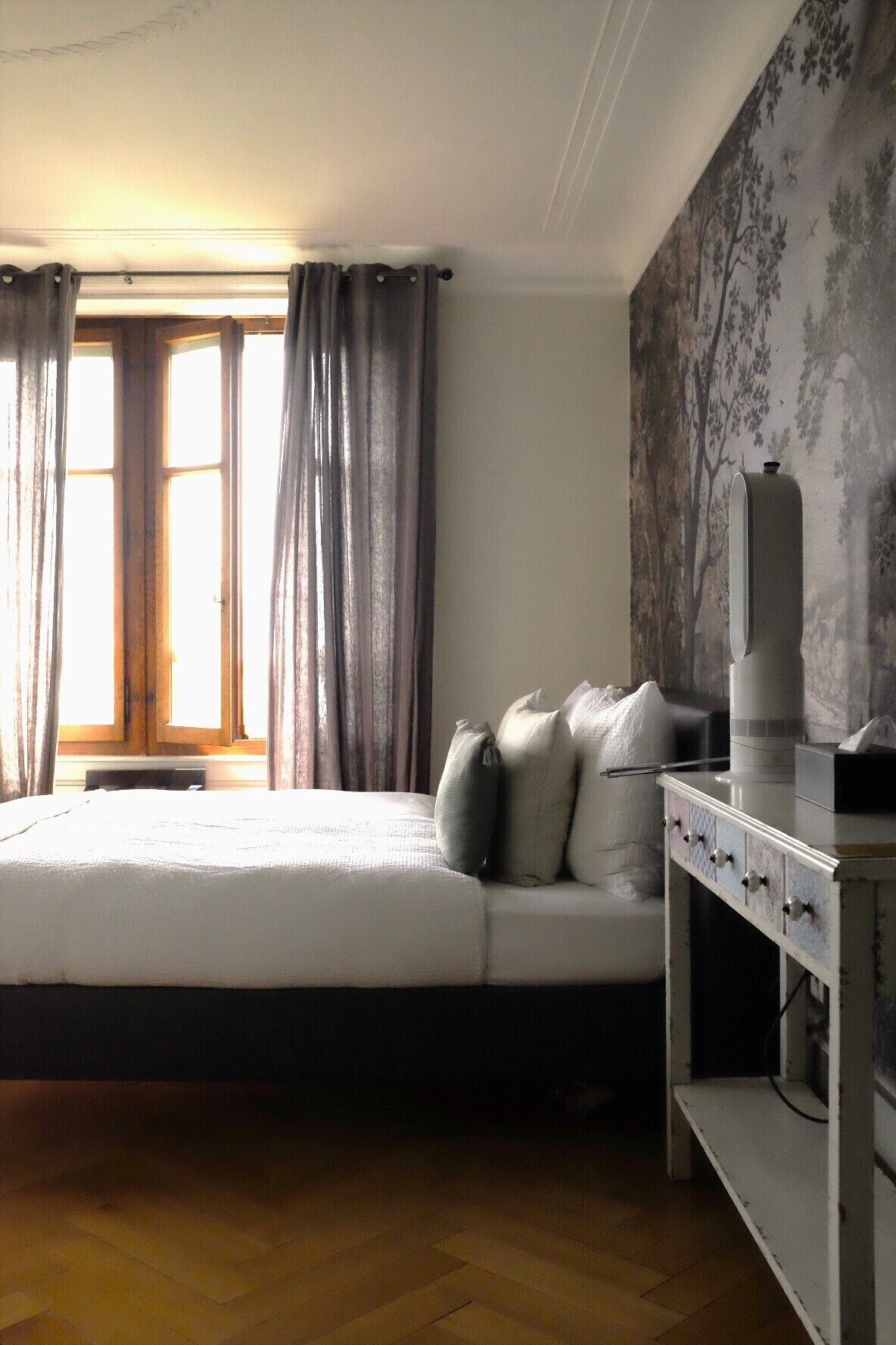 A bedroom with a bed, a nightstand, a lamp, and a window with curtains.