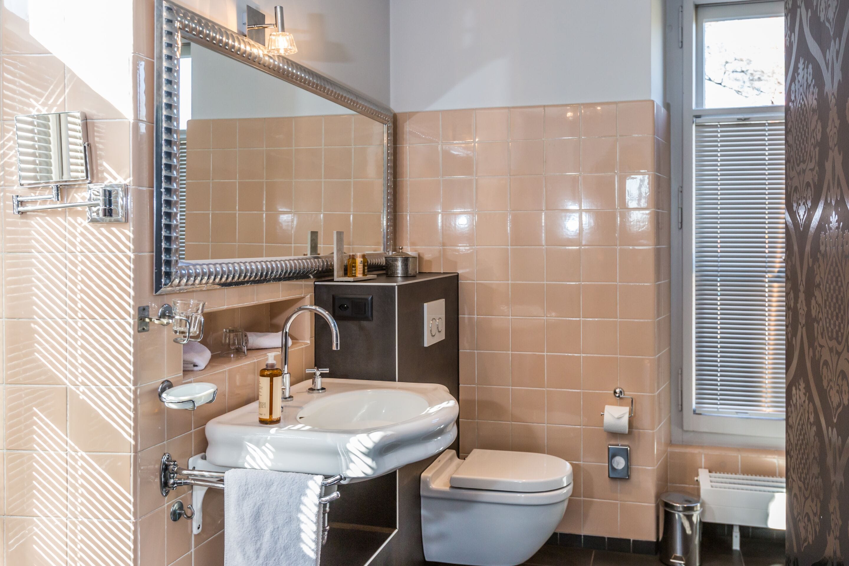 A modern bathroom with a large mirror, a sink, and a toilet.