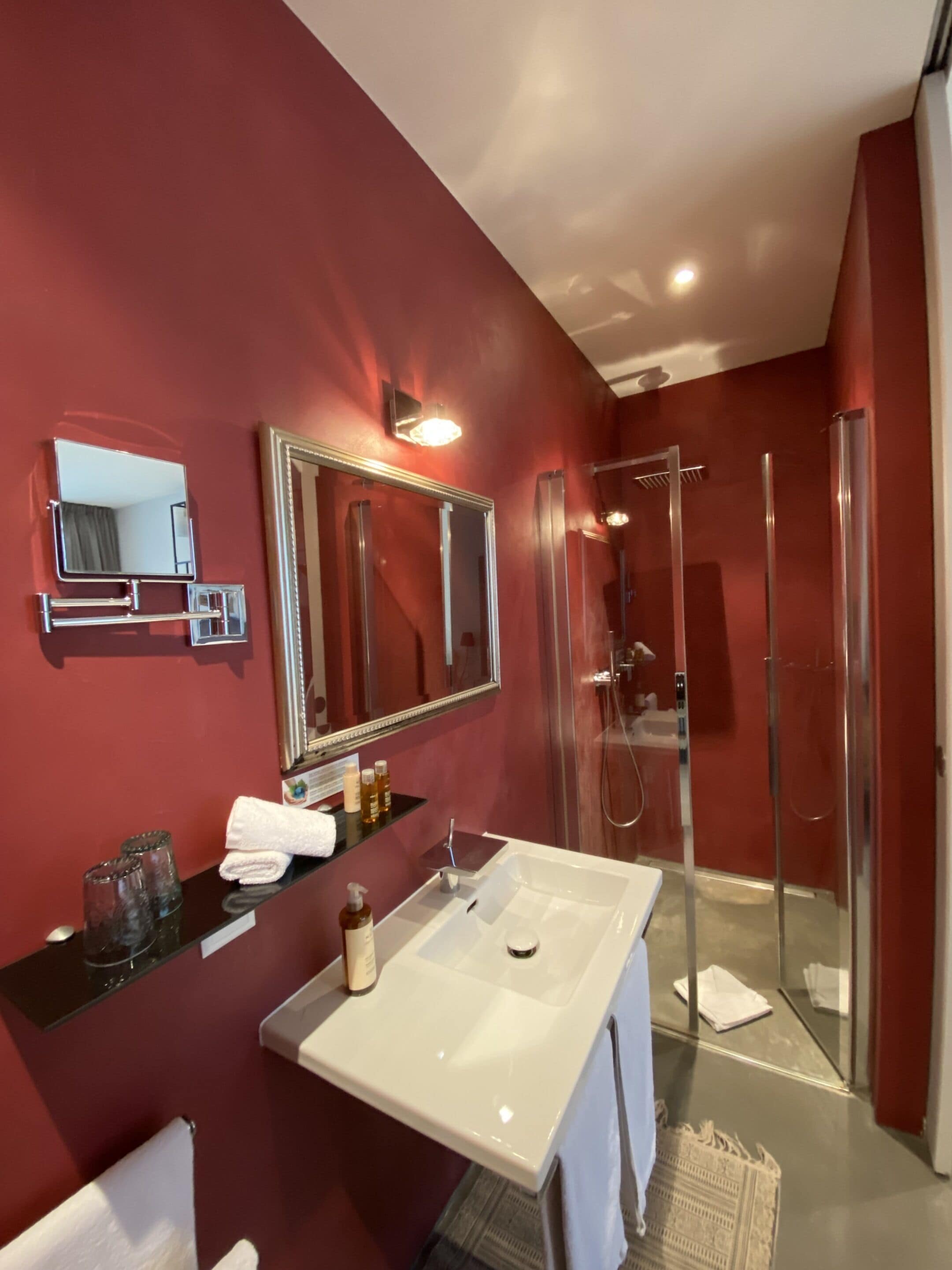 A modern bathroom with a large mirror, a white sink, and a glass-enclosed shower.