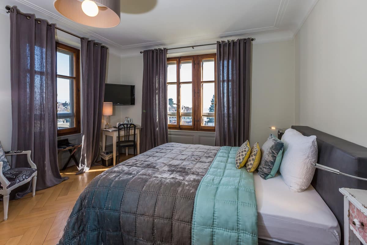 A bedroom with a bed, a desk, a chair, and a TV.