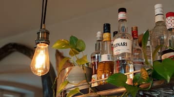Una balda amb diverses ampolles de licor i una làmpada penjant.