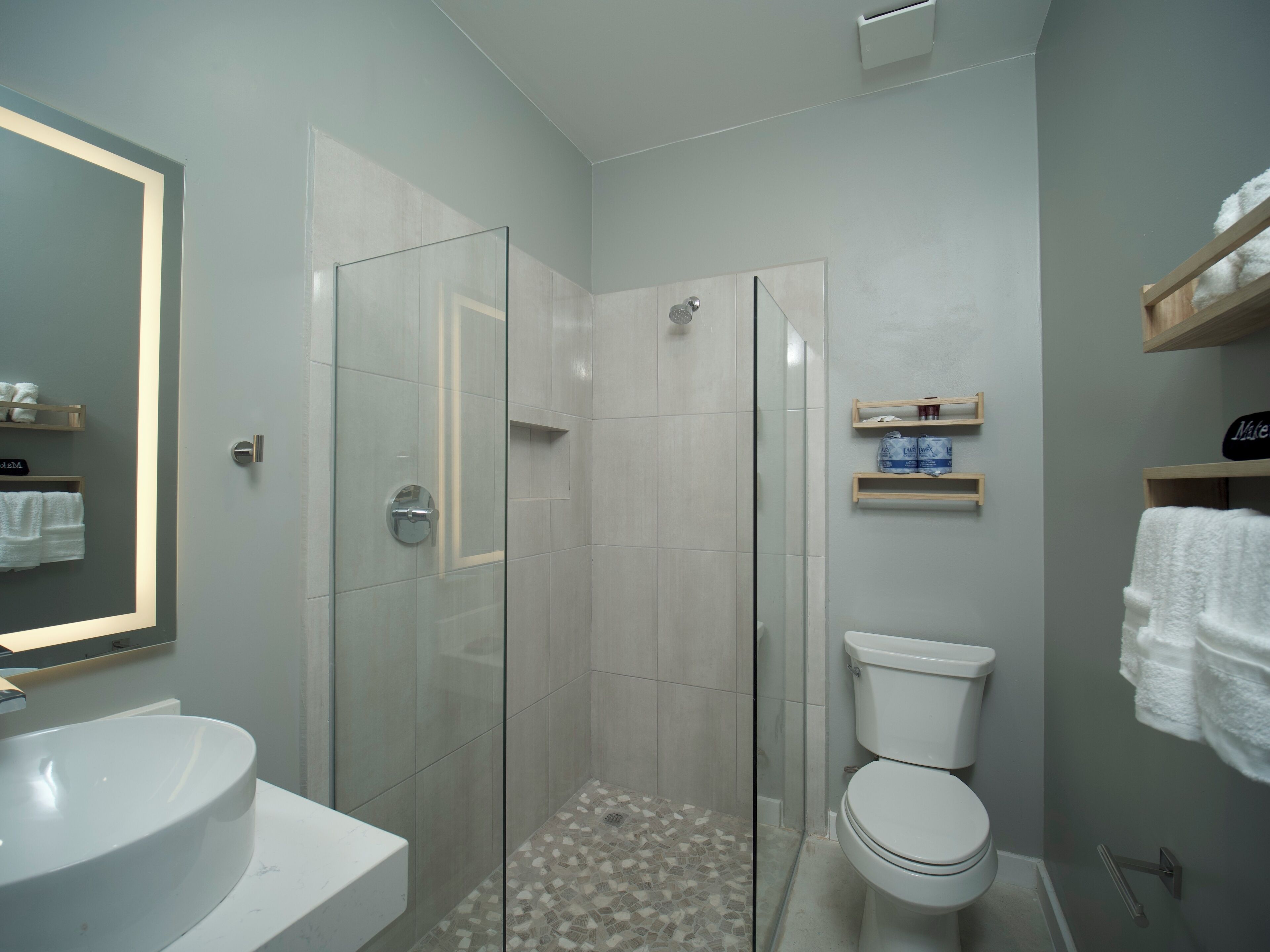 Ein modernes Badezimmer mit einer Duschkabine, einem weißen Waschbecken und einer Toilette.