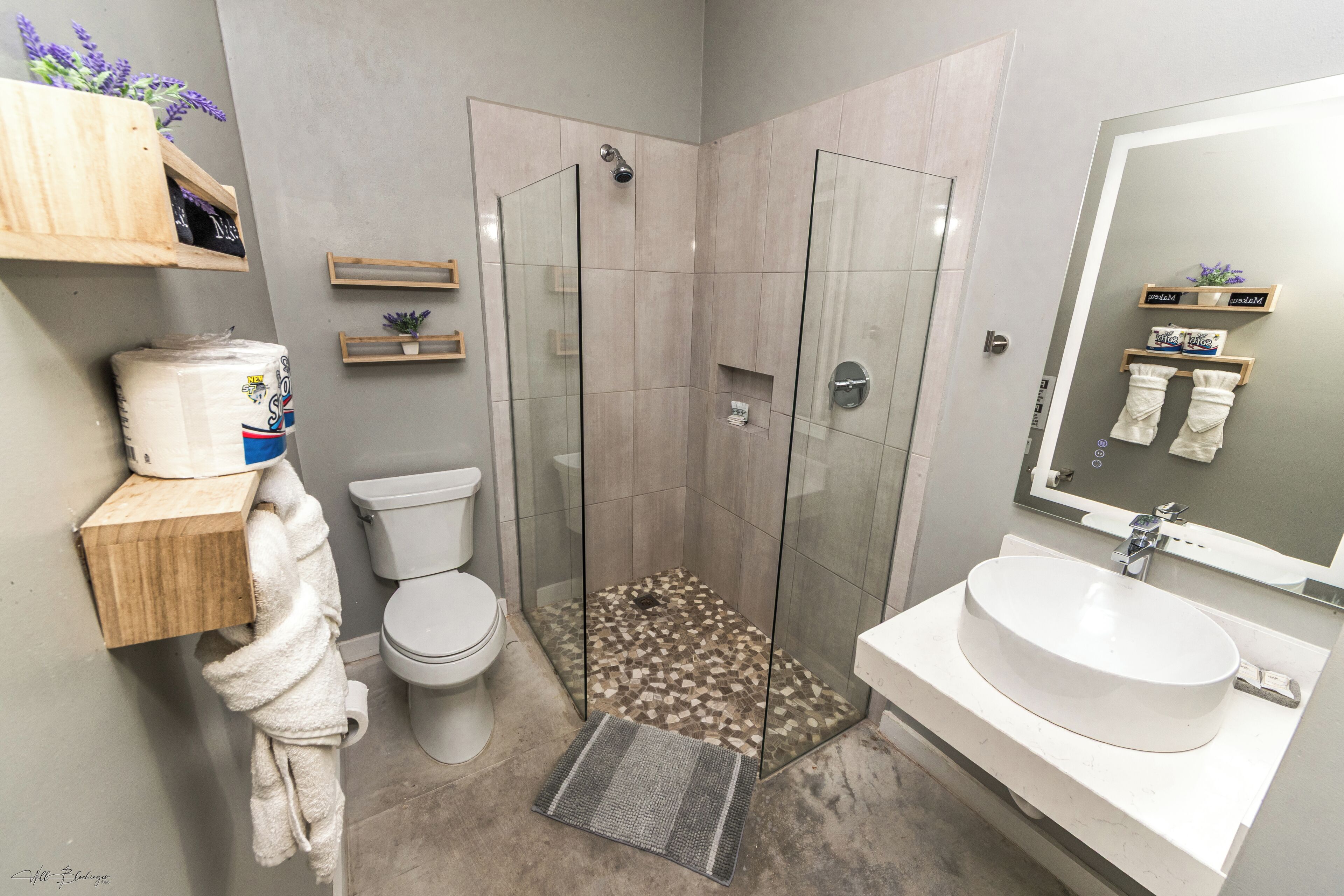 Une salle de bain moderne avec une douche à parois de verre, des toilettes, un lavabo avec un miroir et un porte-serviettes.