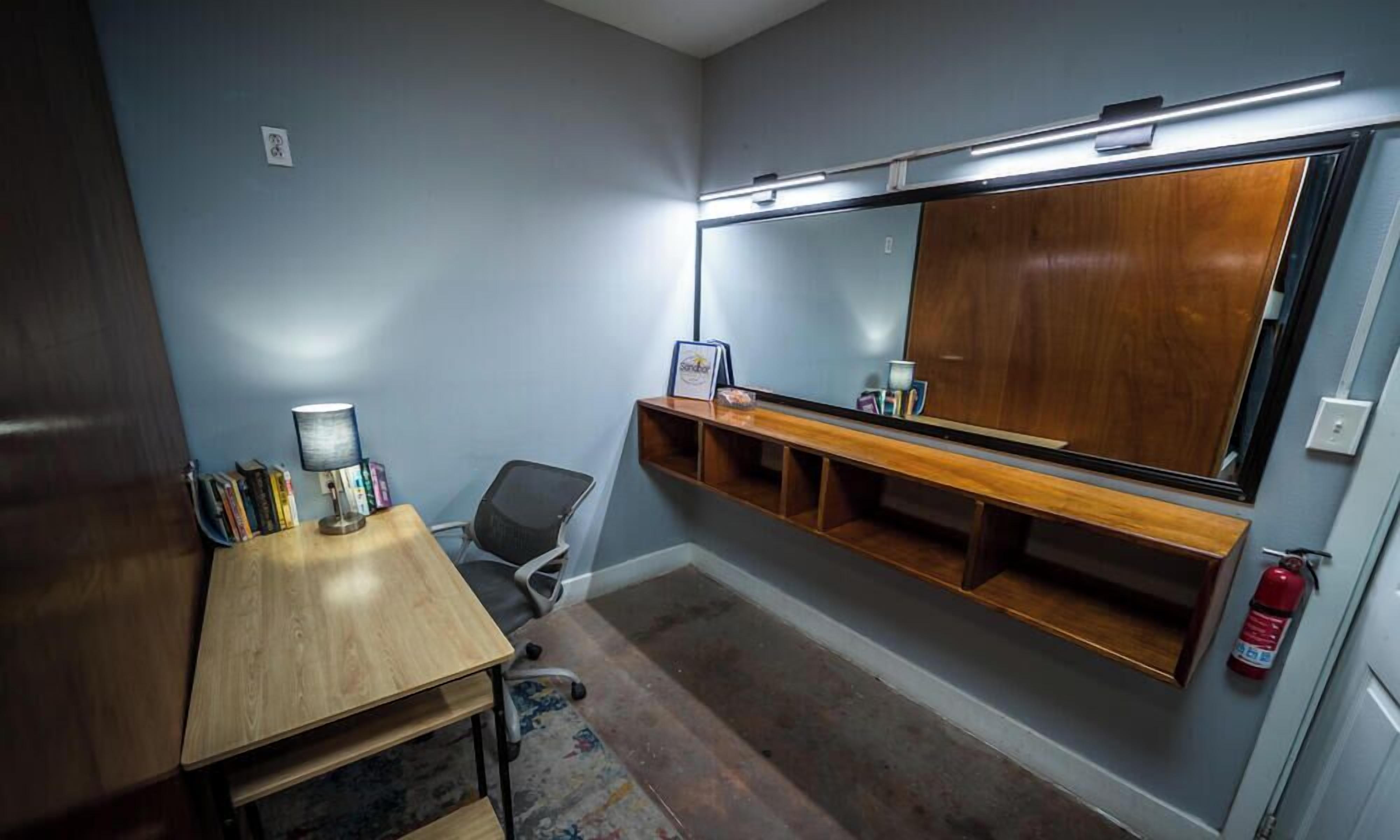 Una habitación con escritorio, silla y un espejo grande.