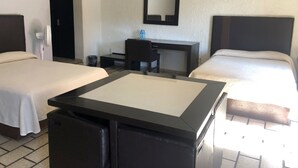 A hotel room with two beds, a desk, a chair, a small trash bin, and a mirror on the wall. - Hotel Plaza Centro (Tepatitlan de Morelos)