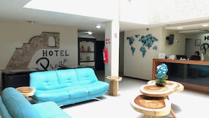 A hotel lobby with a blue sofa, wooden tables, a reception desk, and a world map on the wall. - Hotel Plaza Centro (Tepatitlan de Morelos)