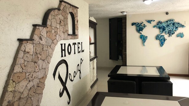 A hotel interior with a stone wall, a 'HOTEL' sign, a world map mural, and a modern reception desk. - Hotel Plaza Centro (Tepatitlan de Morelos)