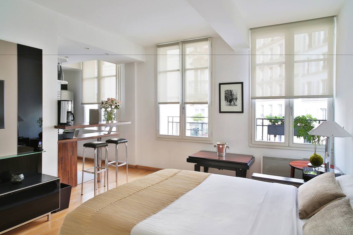 Una habitación de hotel moderna con una cama grande, un escritorio y una kitchenette.