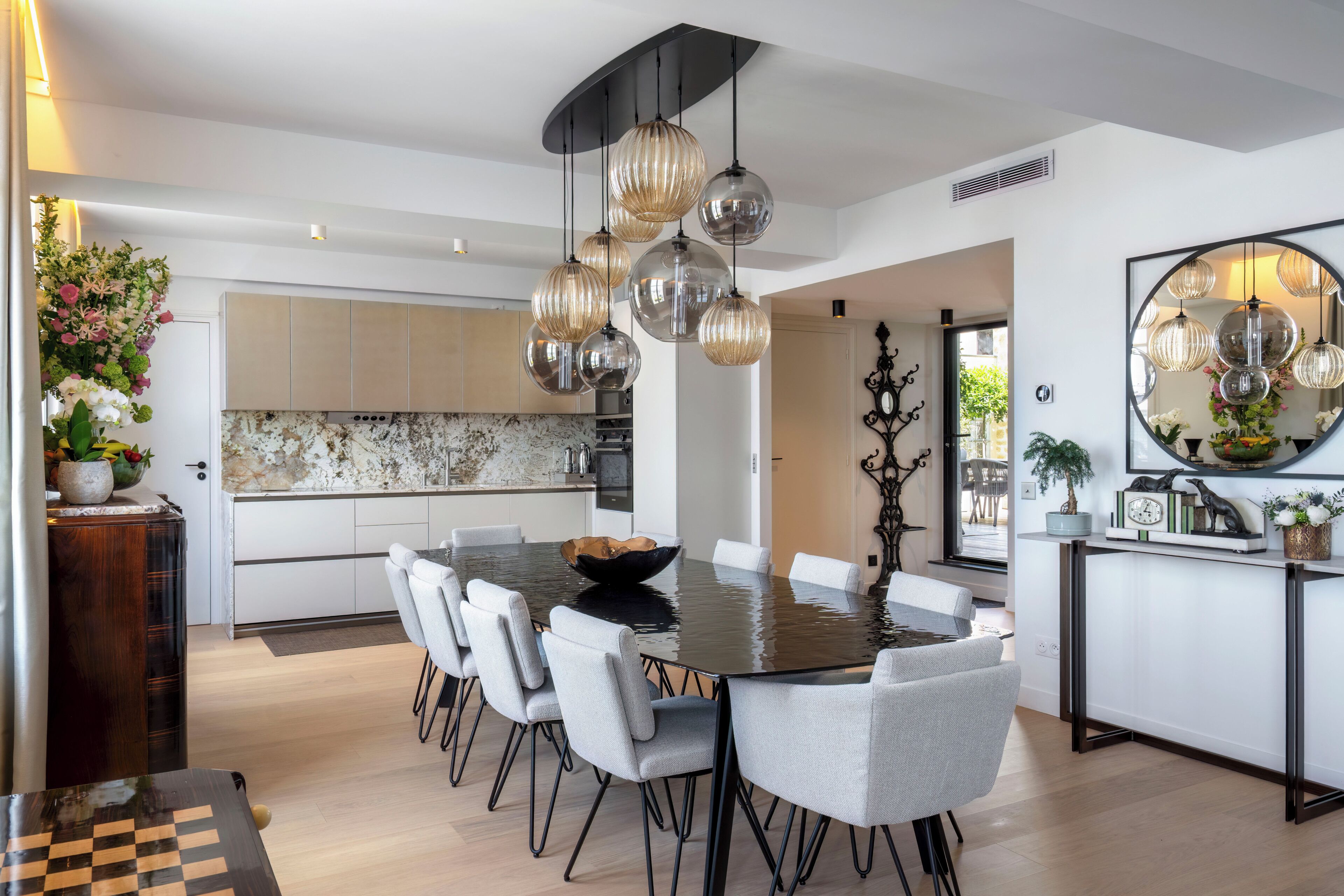 A modern kitchen with a dining area, featuring a large round table, multiple chairs, and pendant lighting.