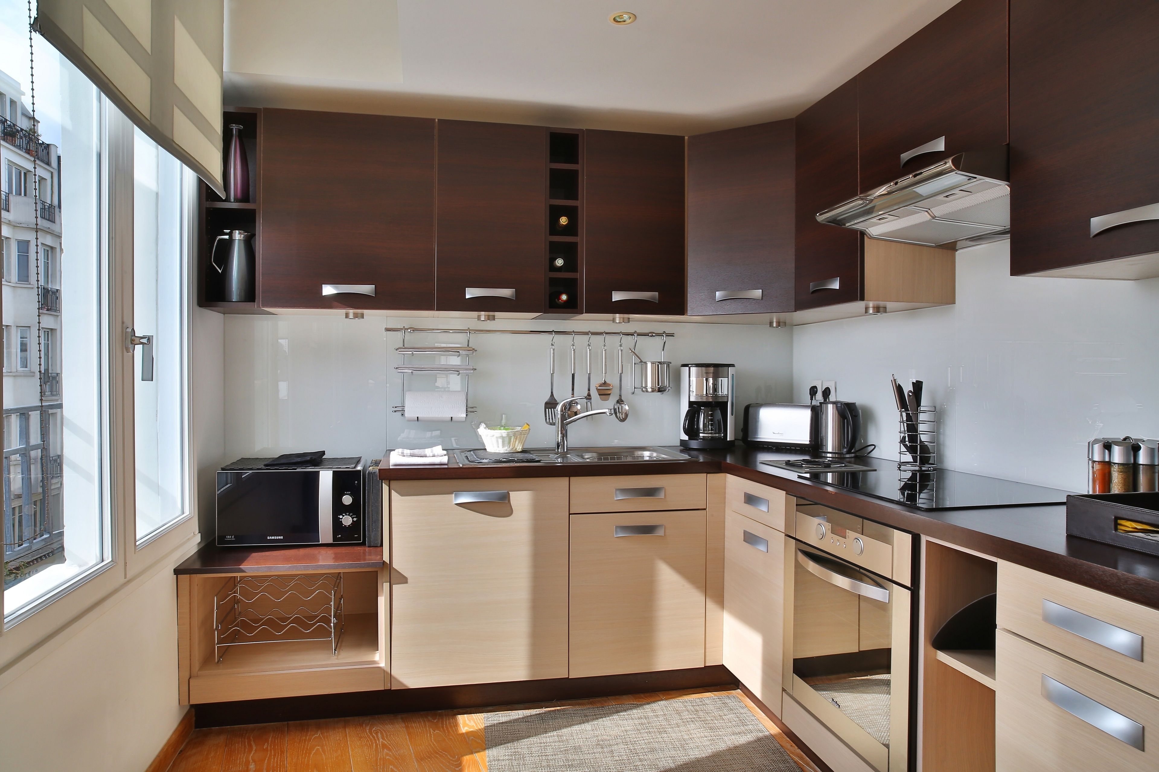 Une cuisine moderne avec des meubles en bois, un four encastré et un four à micro-ondes.