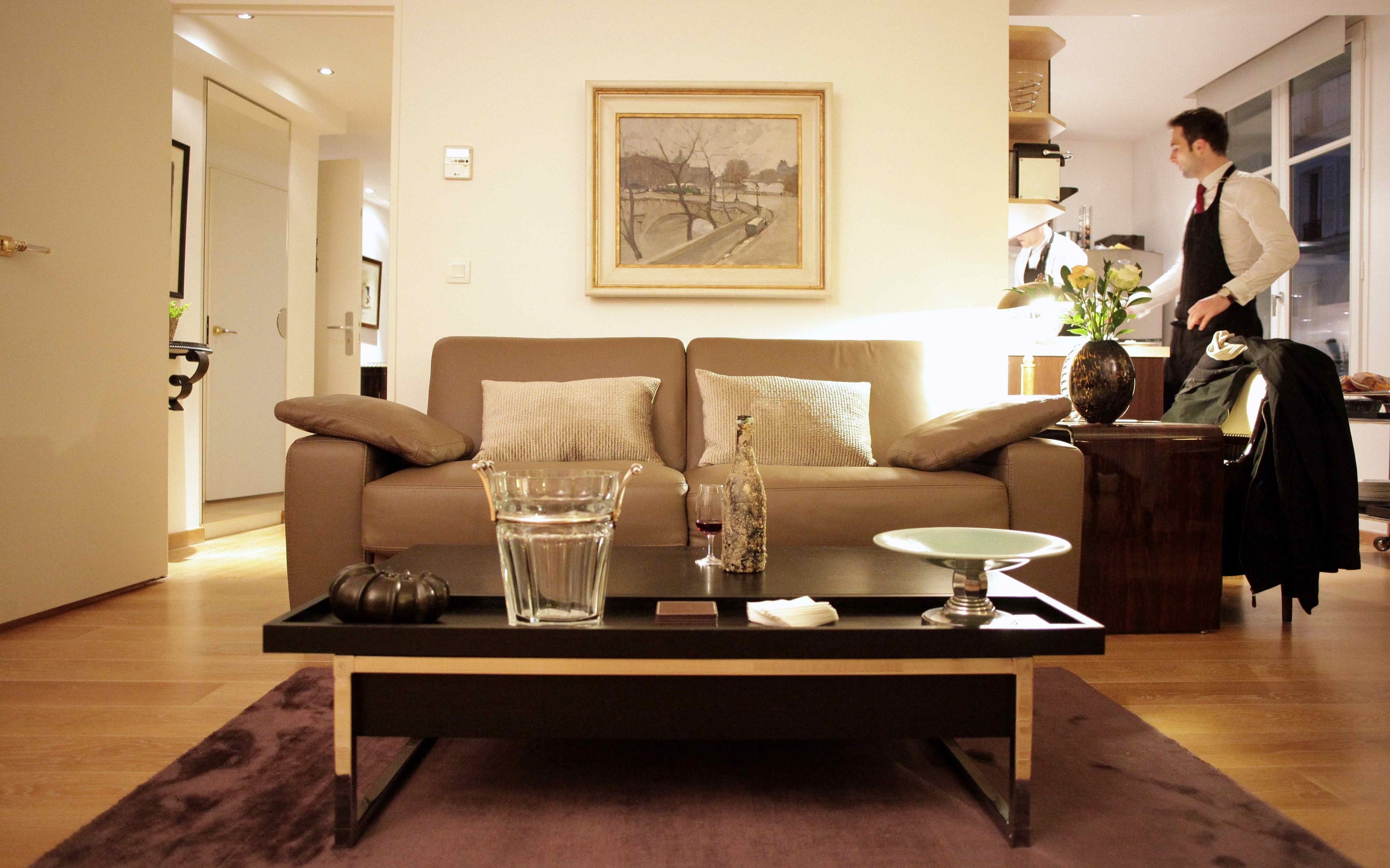 A living room with a sofa, a coffee table with a bottle and glass, and a painting on the wall.