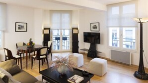 A modern living room with a dining area, a fireplace, and large windows. - Montmartre Residence (Paris)