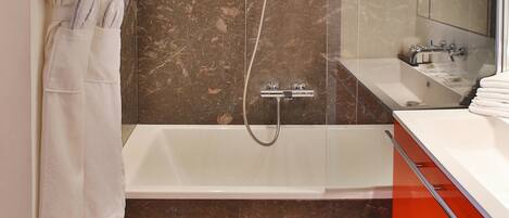 A modern bathroom with a large bathtub, a shower, and a vanity with a mirror.