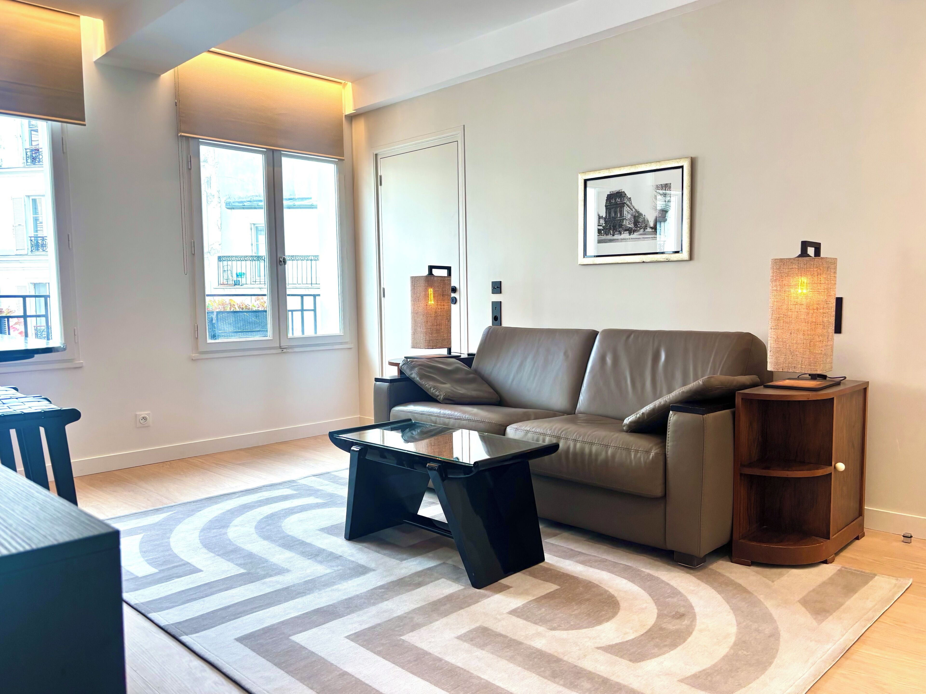 A modern living room with a leather sofa, a glass coffee table, and a patterned rug.