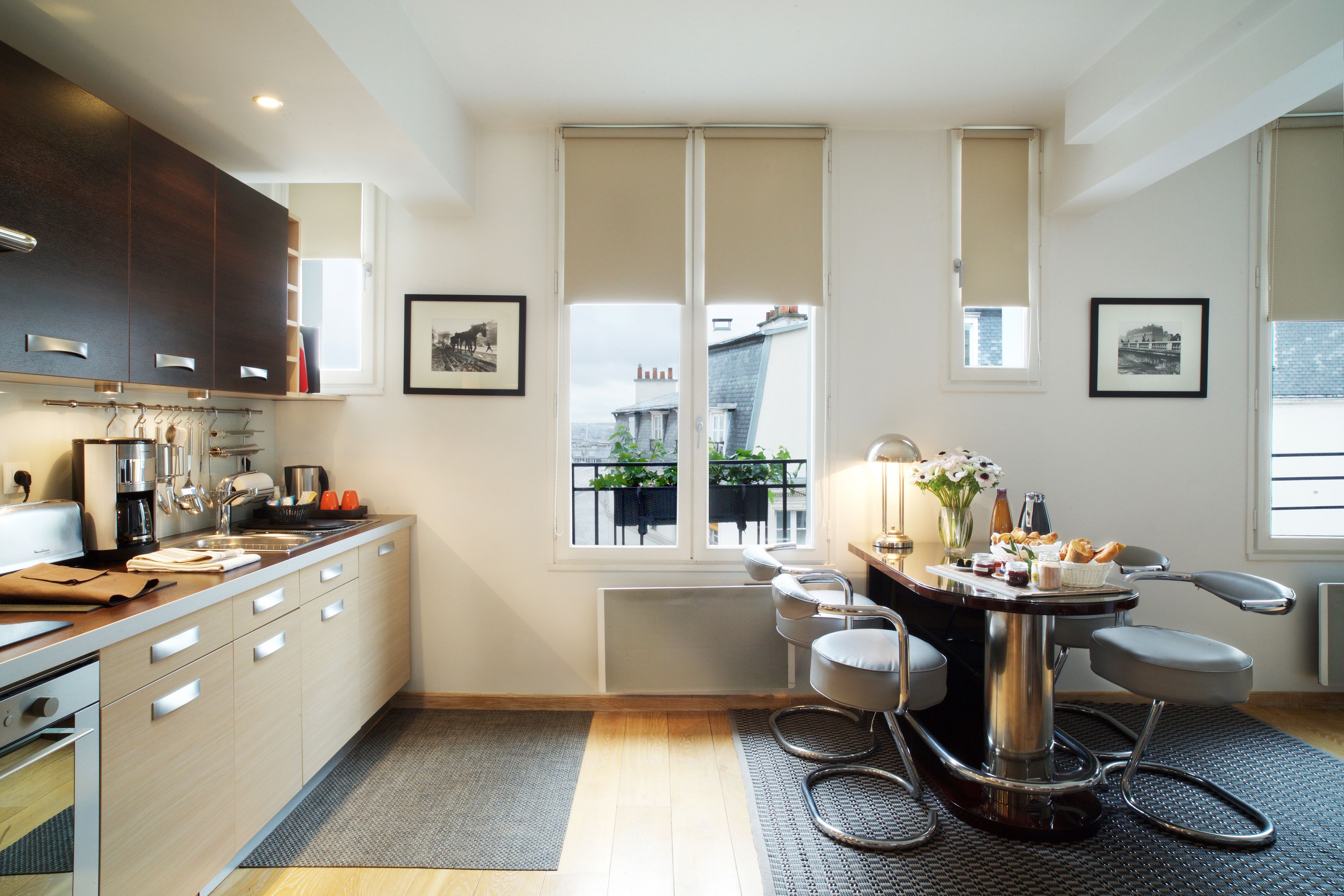 Een moderne keuken met een eethoek, met een groot raam, een eettafel met stoelen en een keukenblad met apparatuur.