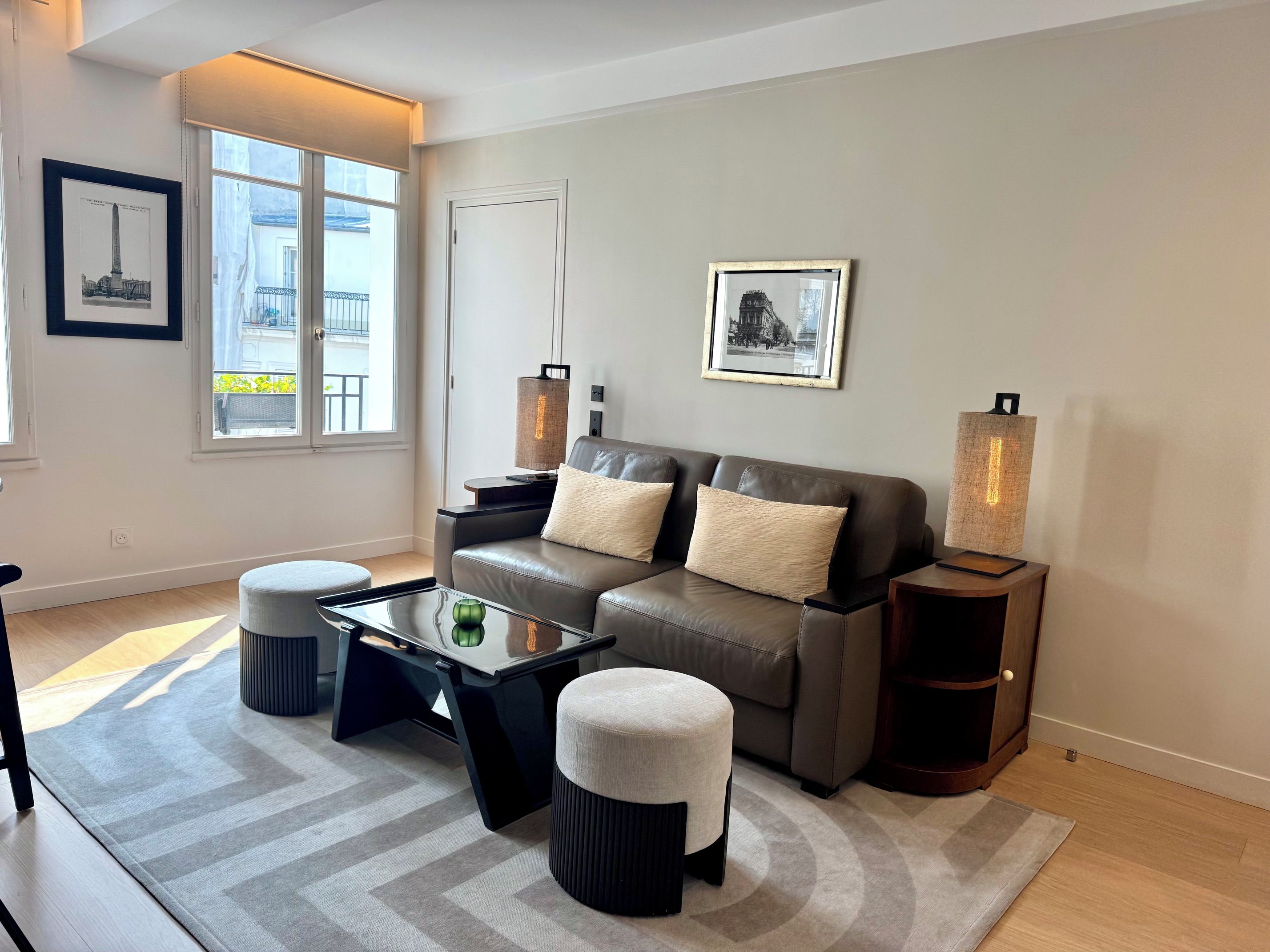 A modern living room with a sofa, ottomans, a coffee table, and two floor lamps.