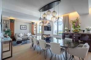 A modern living room with a dining area, a sofa, a TV, and a large window. - Montmartre Residence (Paris)